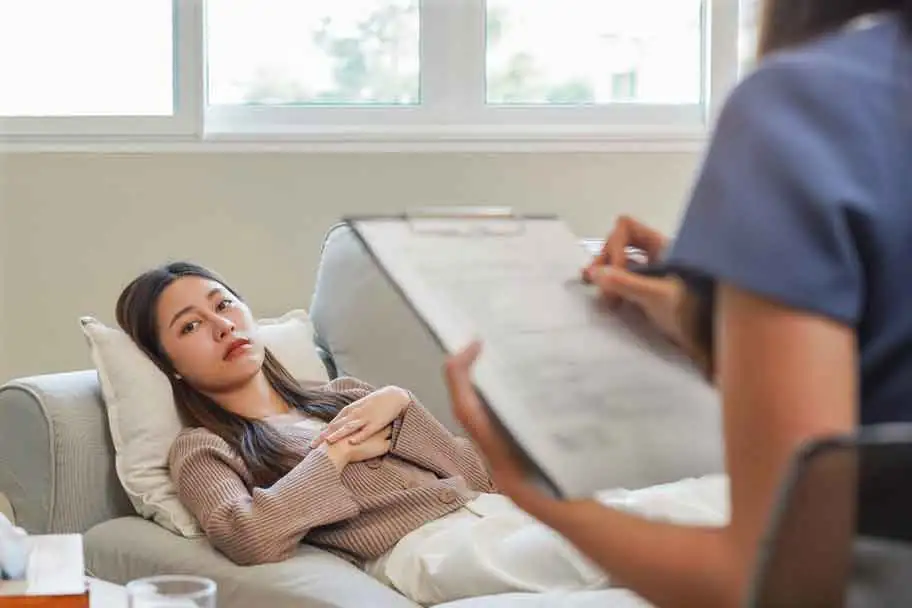 patient lying down while the therapist is writing down her issues