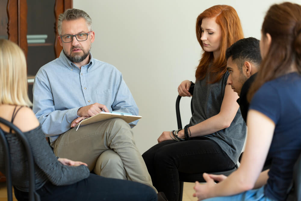 What to Expect at a Luxury Addiction Treatment Facility in California 1 Therapist talking to a group of patients in a group session in a rehab center