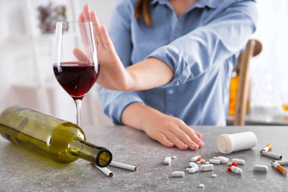 Alcohol and Trazodone: A Dangerous Mix 1 Young woman refusing glass of wine and drugs while sitting at table