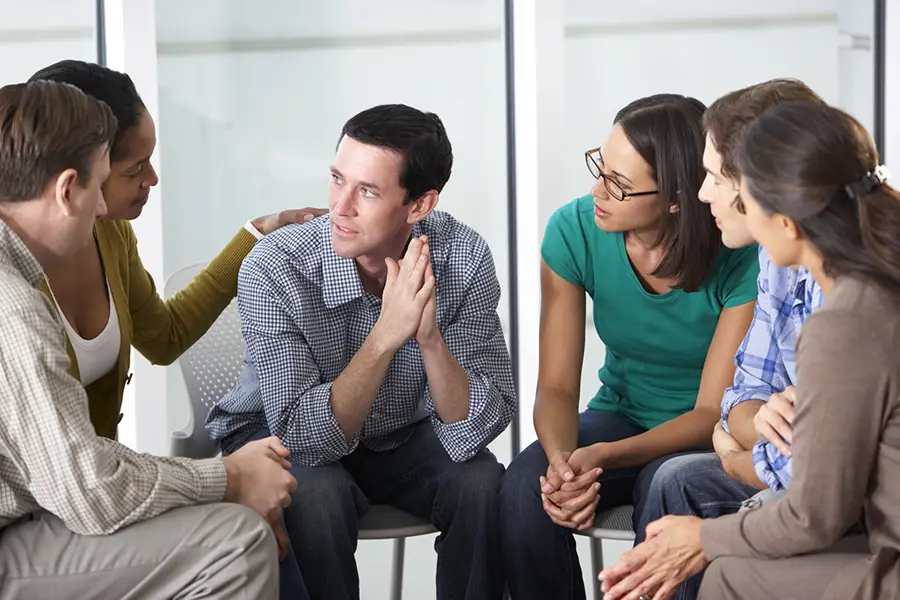 support group sitting in a circle, listening to a man share his experience with alcohol abuse during a therapy session.