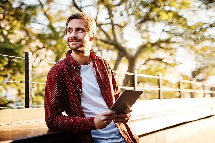 man holding a tablet outdoors, symbolizing life progress during recovery from opioid use disorder.