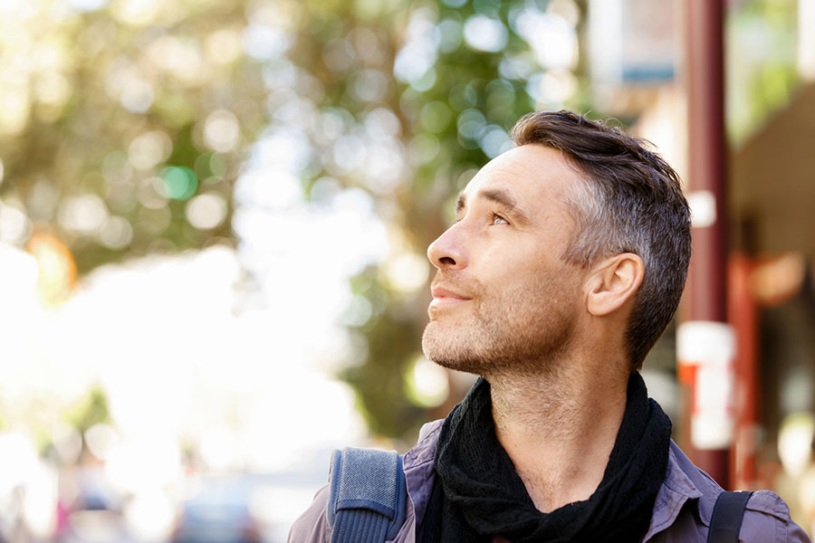 Man looking up thoughtfully outdoors, representing reflection and hope in recovery from prescription drug abuse.