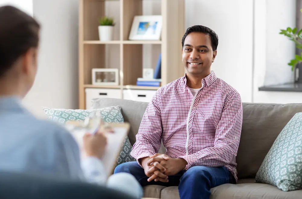 a man talks with a therapist on a couch, illustrating supportive one-on-one care in methamphetamine addiction treatment.