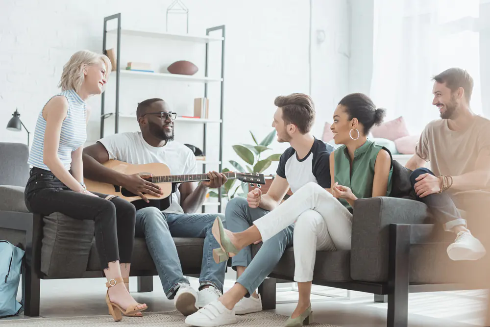 Multicultural group of young people sitting in living room.