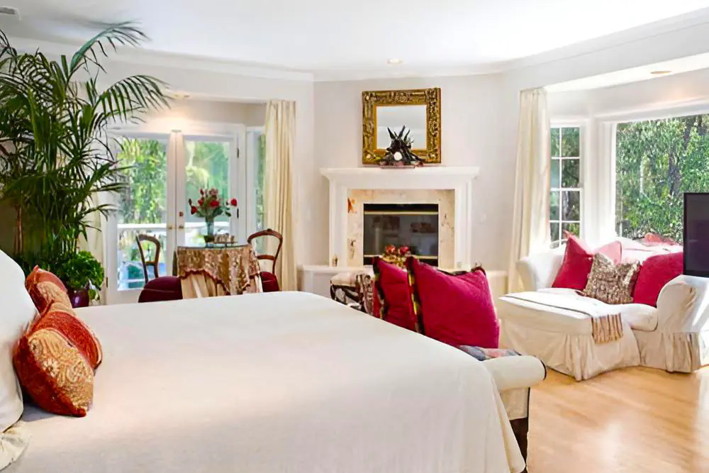bedroom with a fireplace, sitting area and garden-facing windows