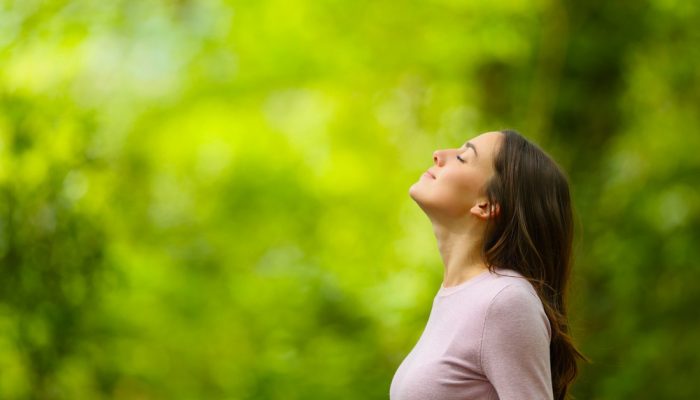 a relaxed woman breathing fresh air in a green forest