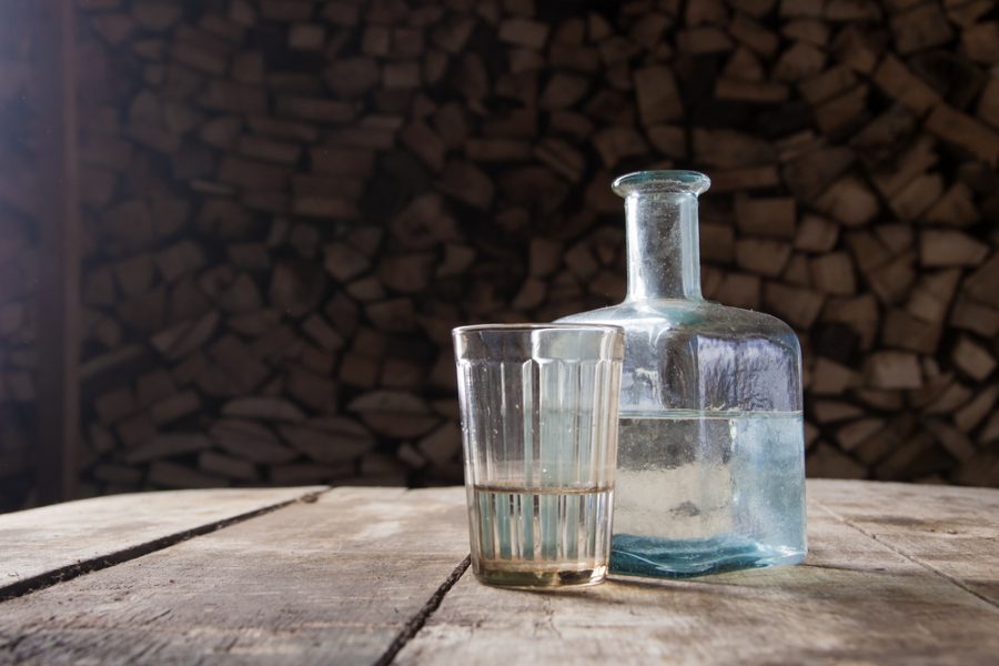 A glass and bottle of clear vodka on a table, illustrating the concept of does vodka ever expire A glass and bottle of clear vodka on a table, illustrating the concept of does vodka ever expire