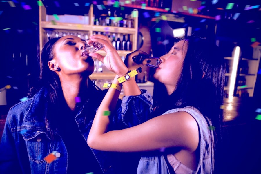 Two women taking shots at a bar party, a moment often linked to getting tipsy quickly in social settings Two women taking shots at a bar party, a moment often linked to getting tipsy quickly in social settings